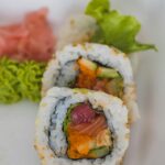 Donations Delicious sushi roll with fresh salmon, avocado, and rice, served with garnishes for a tasty meal.