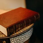 Donations A hardcover book with Hebrew text resting on an intricate patterned tabletop.